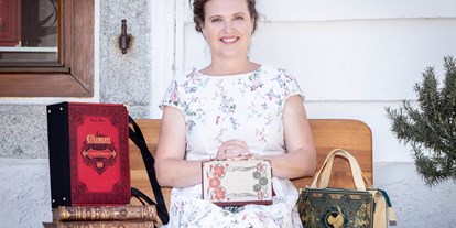 Händler - Produkt-Kategorie: Schmuck und Uhren - Oberösterreich - Künstlerin Bernadette Hartl mit ihren Taschen aus Büchern vor ihrem Atelier sitzend in Steyr. - Bernanderl Upcycling
